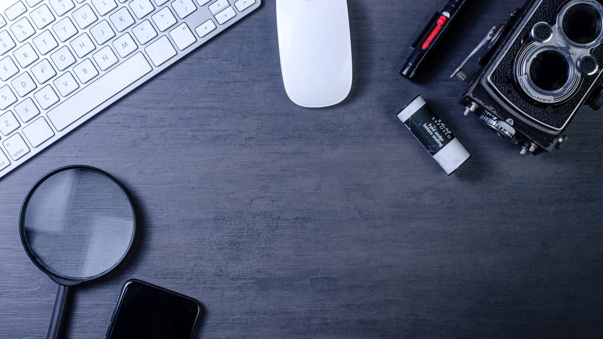 Un smartphone reconditionné posé sur une table de travail en bois à côté d'une loupe et de documents de contrôle qualité.