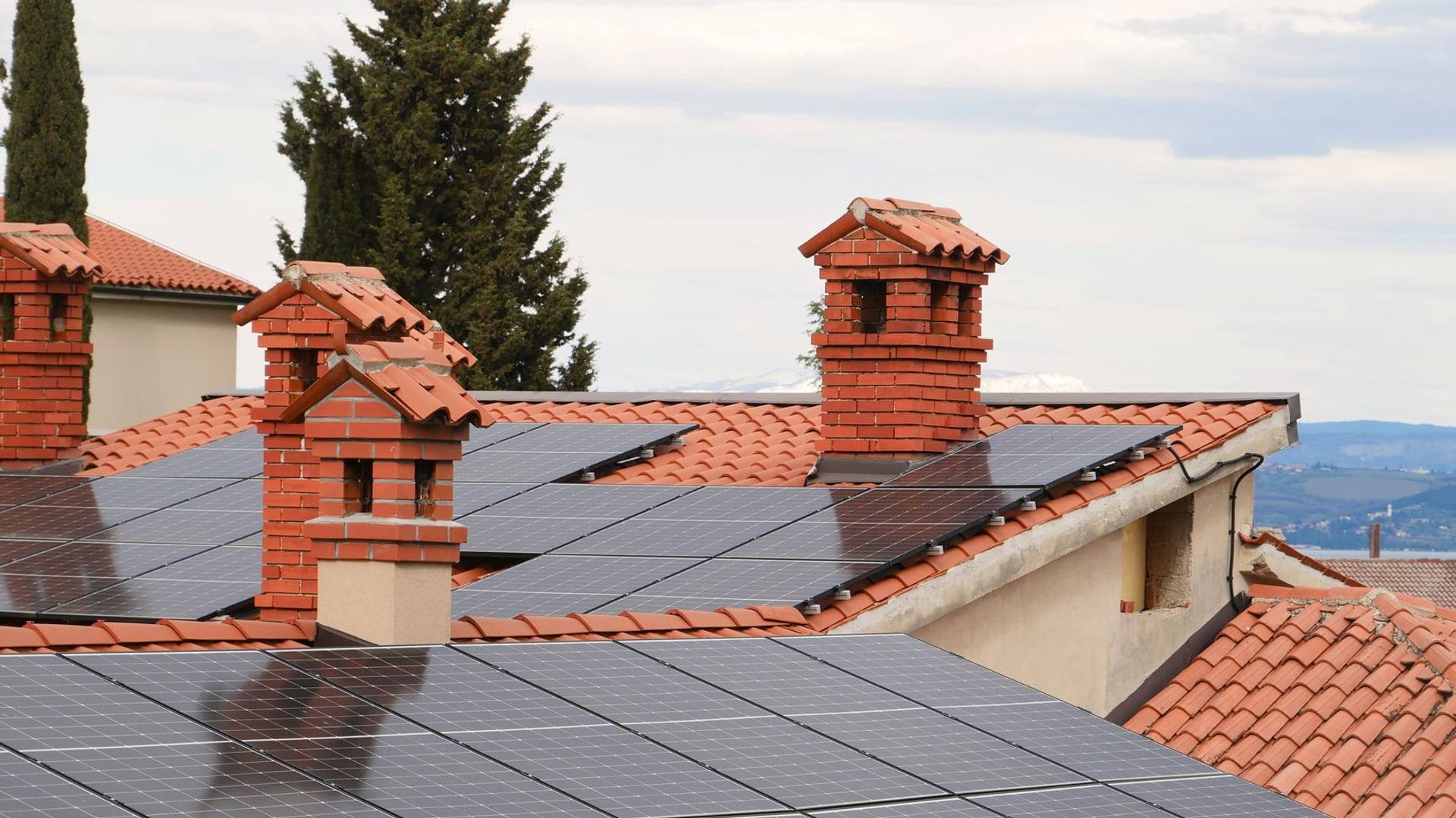 Panneaux photovoltaïques installés sur la toiture en tuiles d'une maison individuelle sous un ciel dégagé.