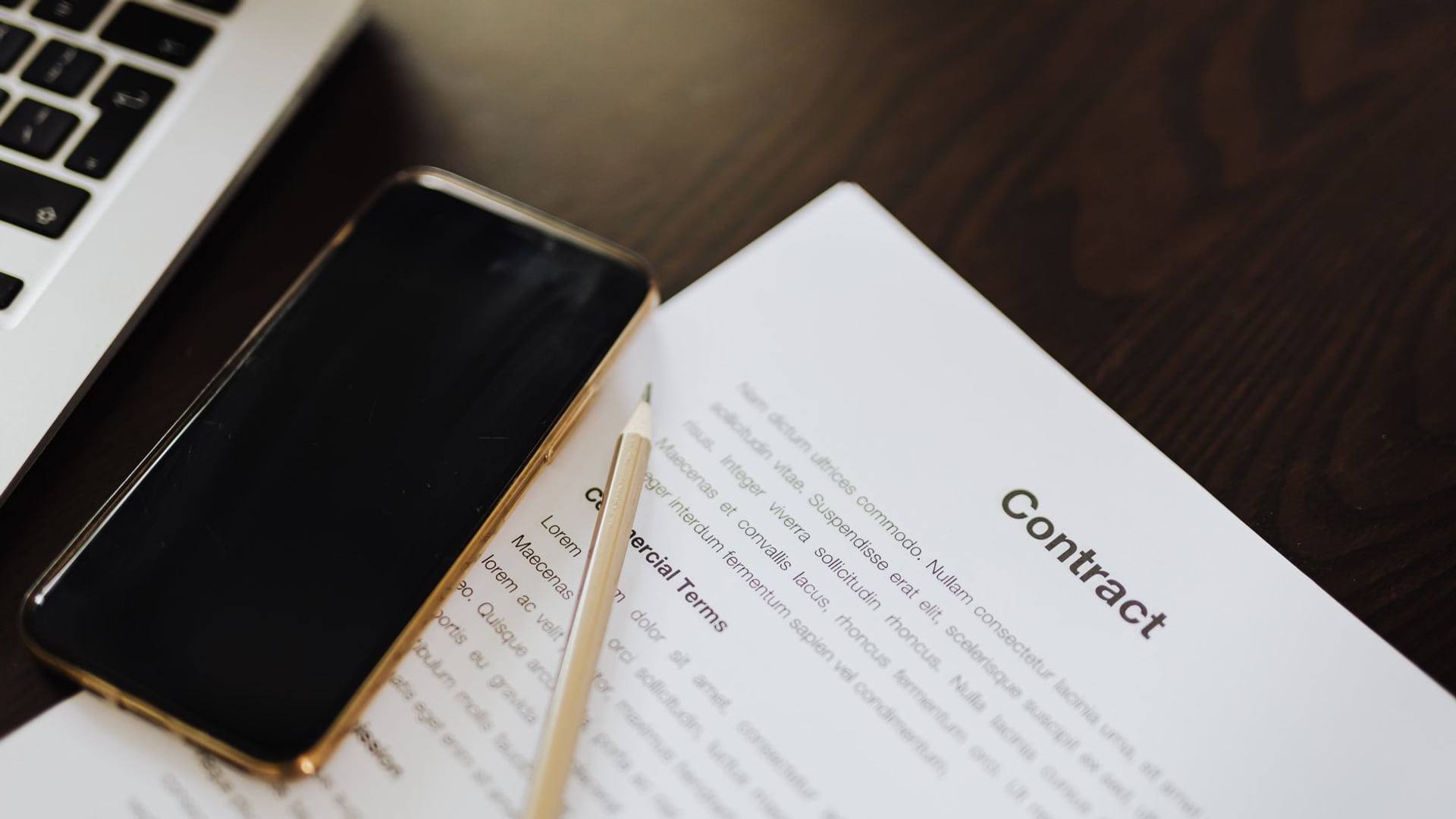 Un smartphone récents reposant à côté d'un contrat de reprise et d'un bloc-notes indiquant des calculs de valeur.