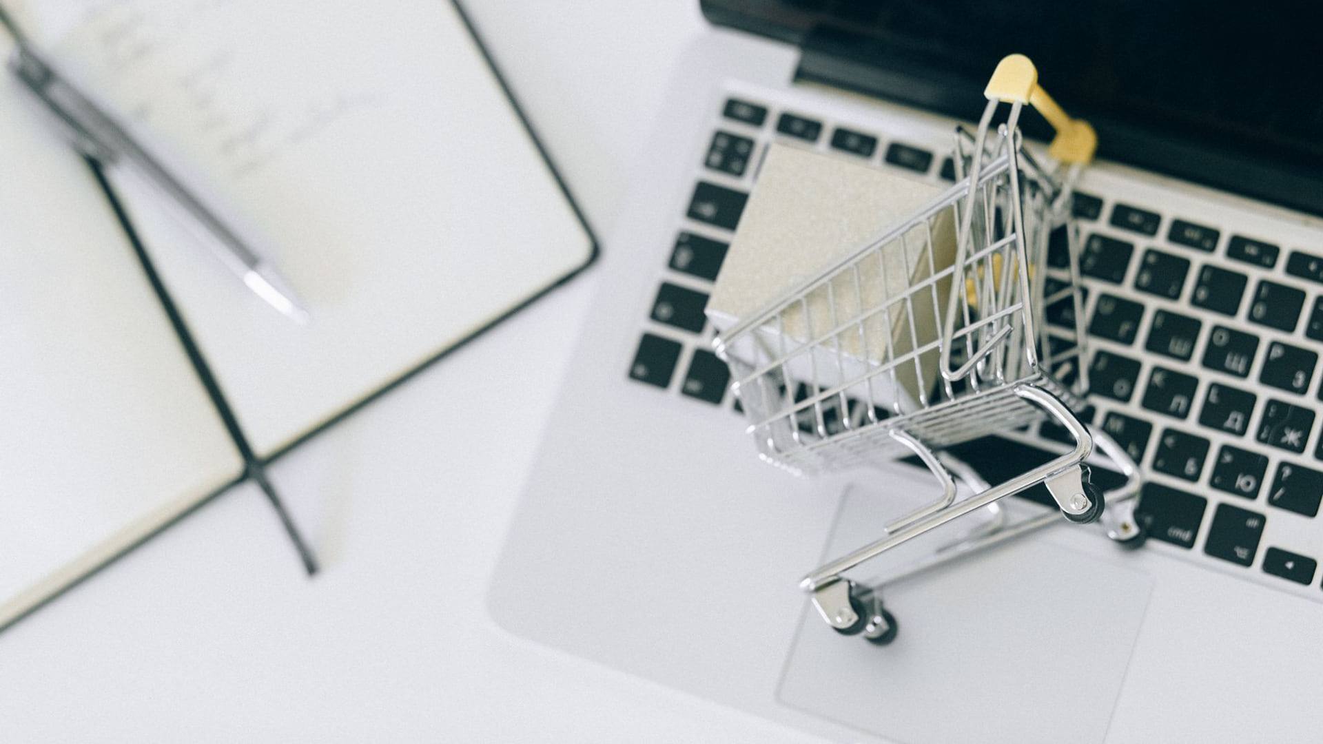 Une calculatrice posée à côté d'un panier d'achat numérique affichant plusieurs lignes d'articles et de réductions