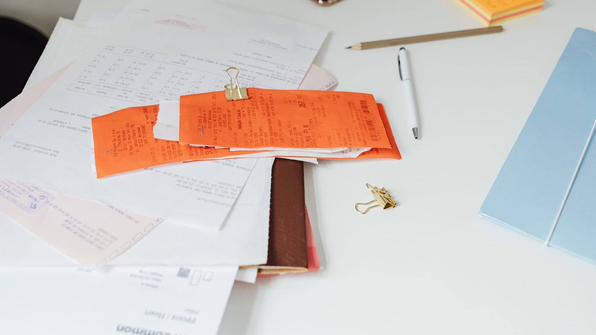 Une personne consultant des documents administratifs et une facture d'électricité à sa table de travail.