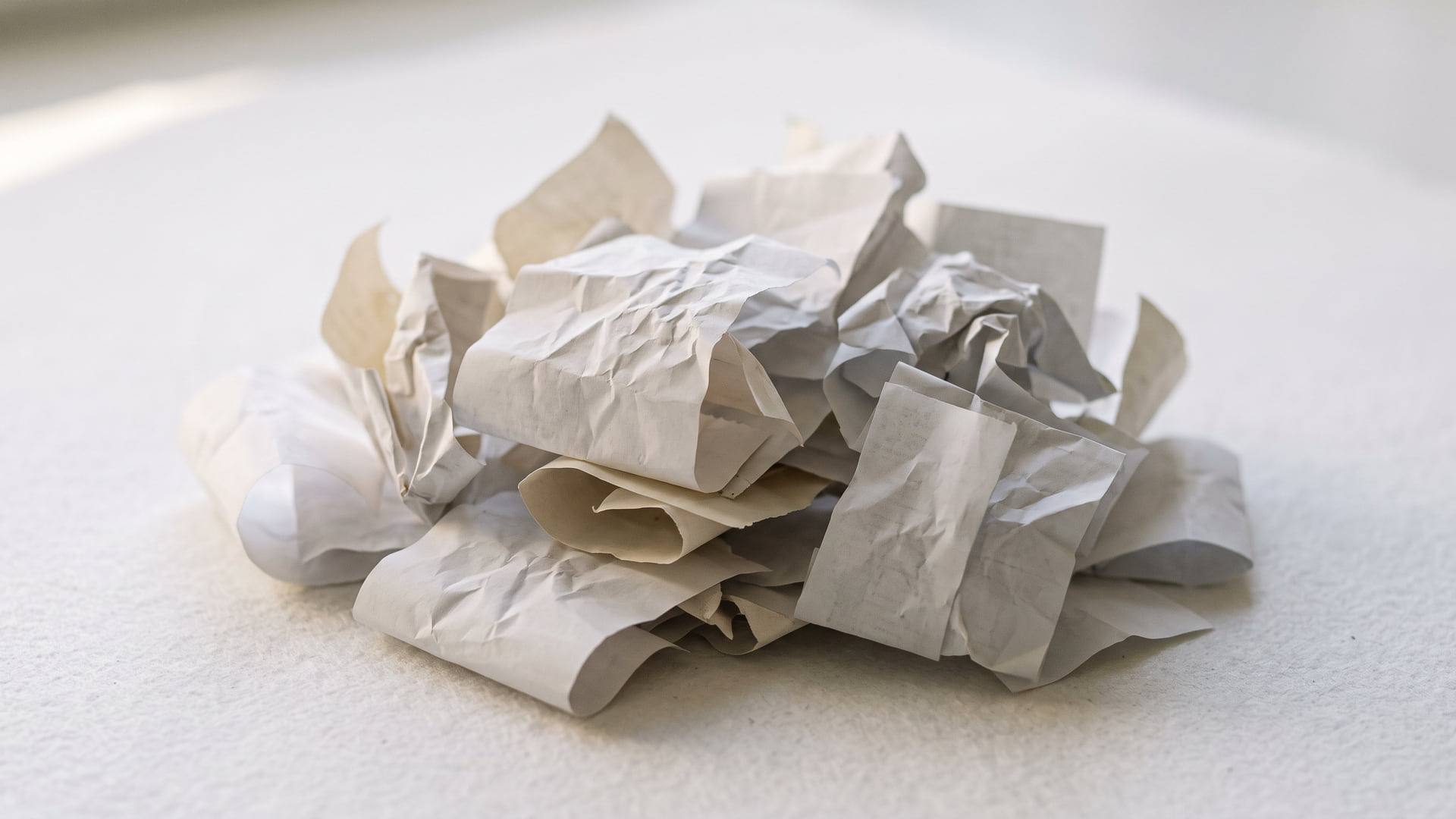 Tickets de caisse en papier thermique froissés et vierges, empilés en désordre sur une surface blanche