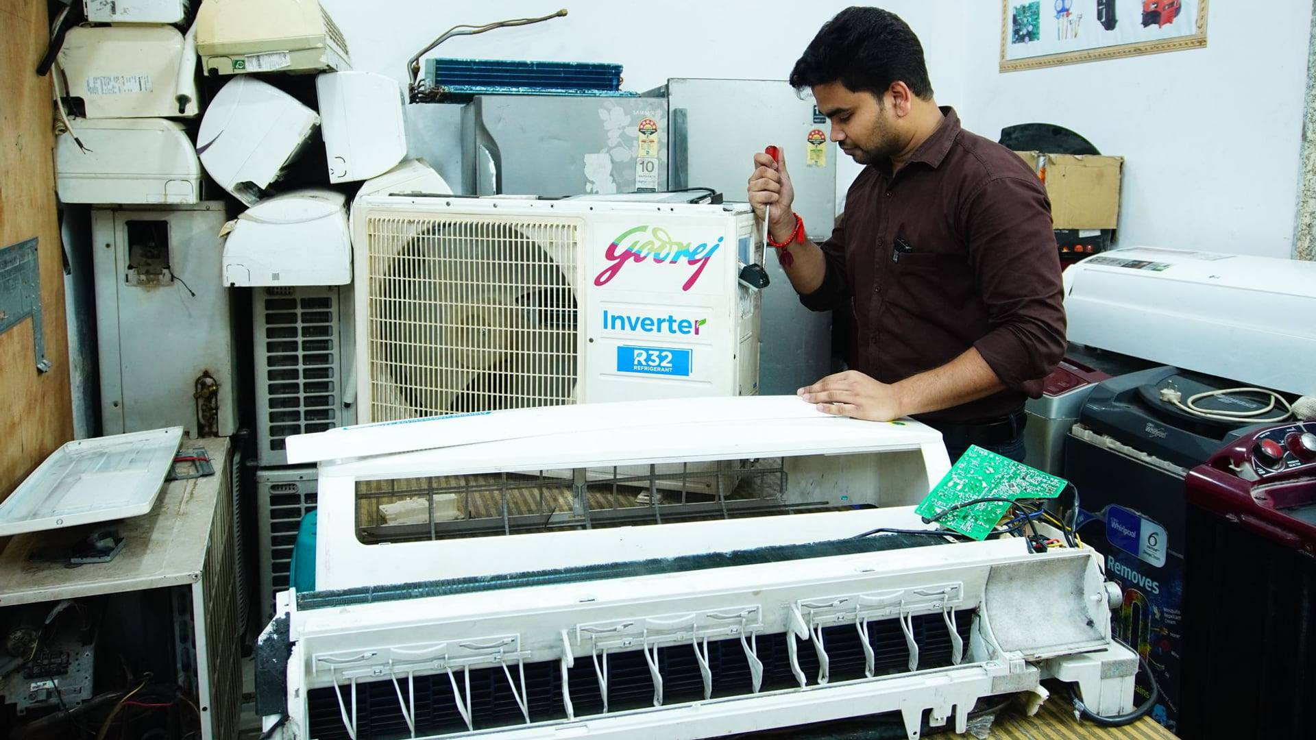 Un technicien qualifié démonte un appareil électroménager défectueux sur un établi de réparation avec des outils professionnels.