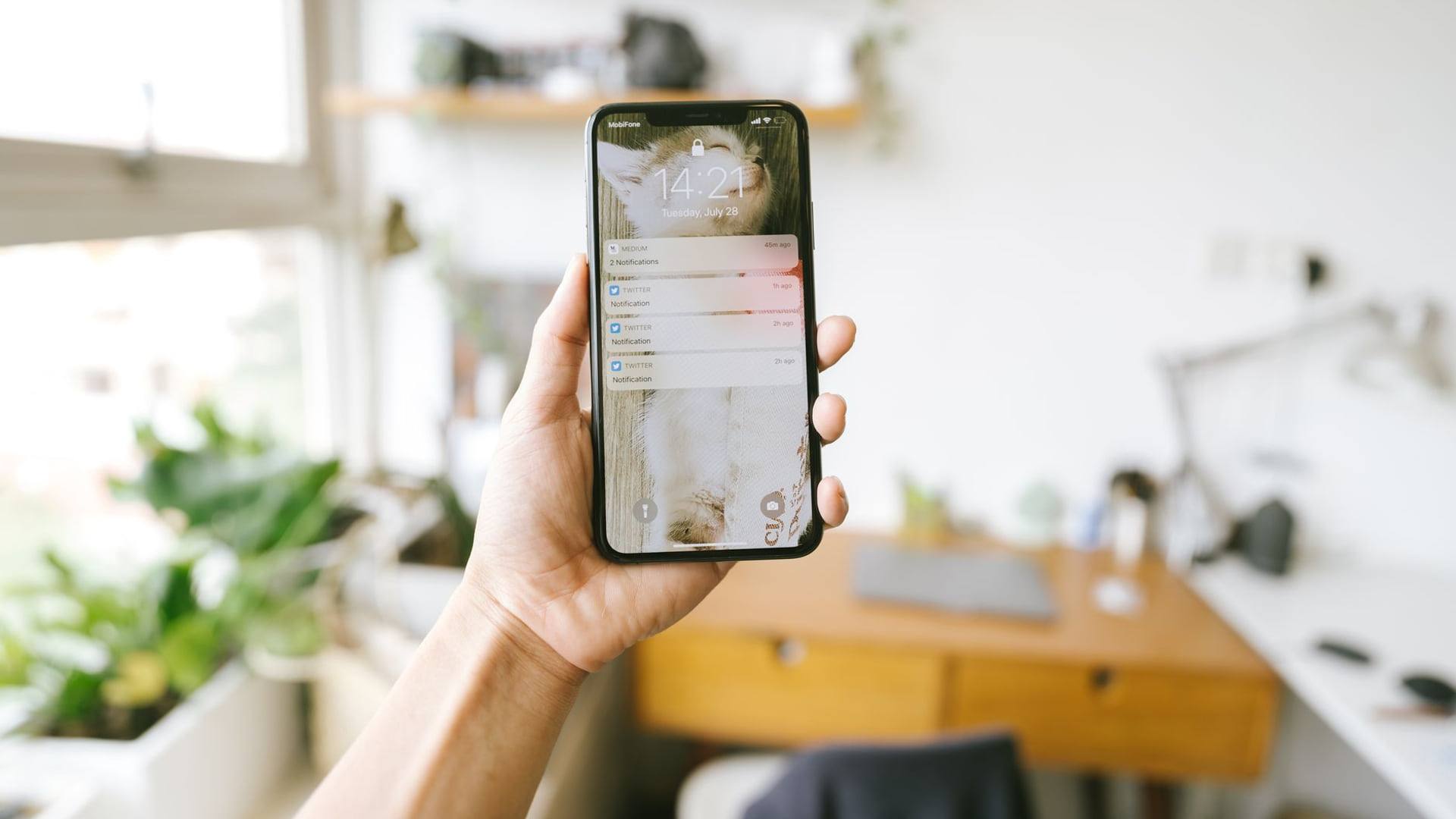 Un smartphone posé sur un bureau en bois affichant un écran de mise à jour du système d'exploitation à côté d'un bloc-notes.