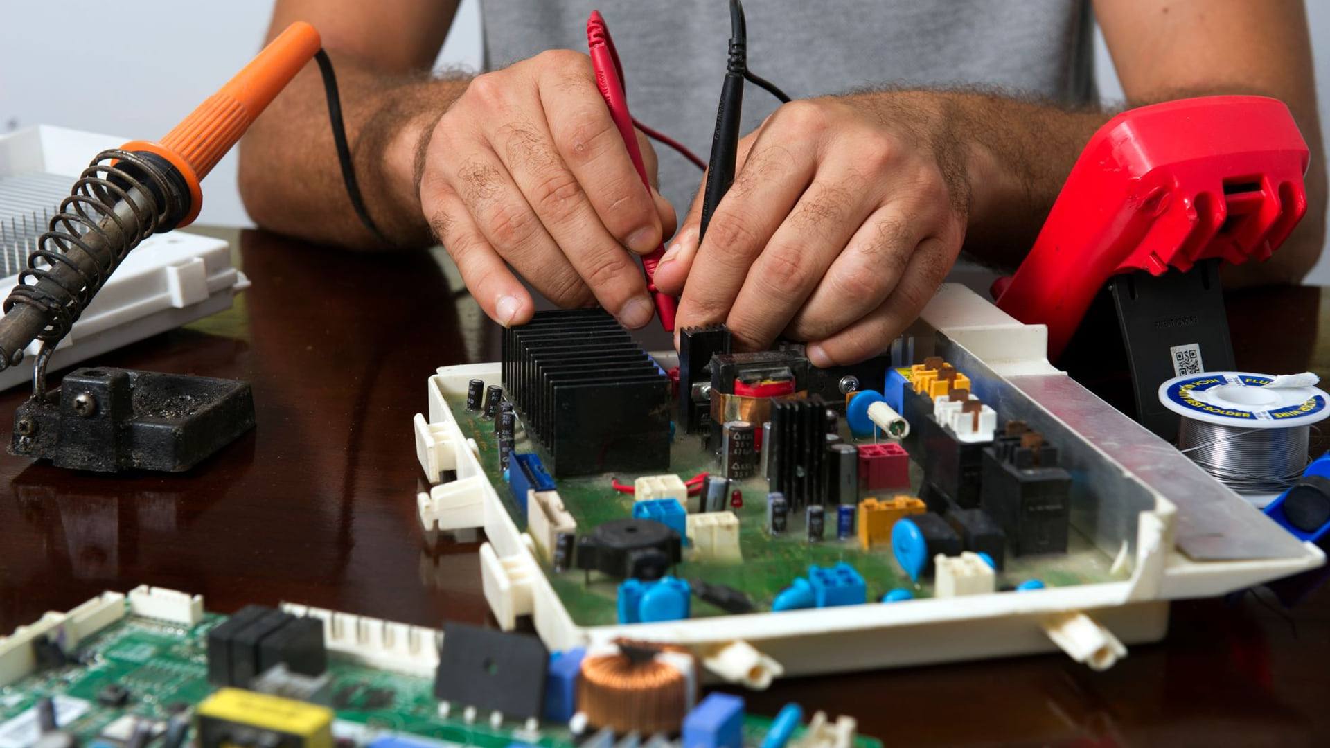 Un technicien contrôlant les composants électroniques d'un lave-linge dans un atelier de reconditionnement d'appareils électroménagers.