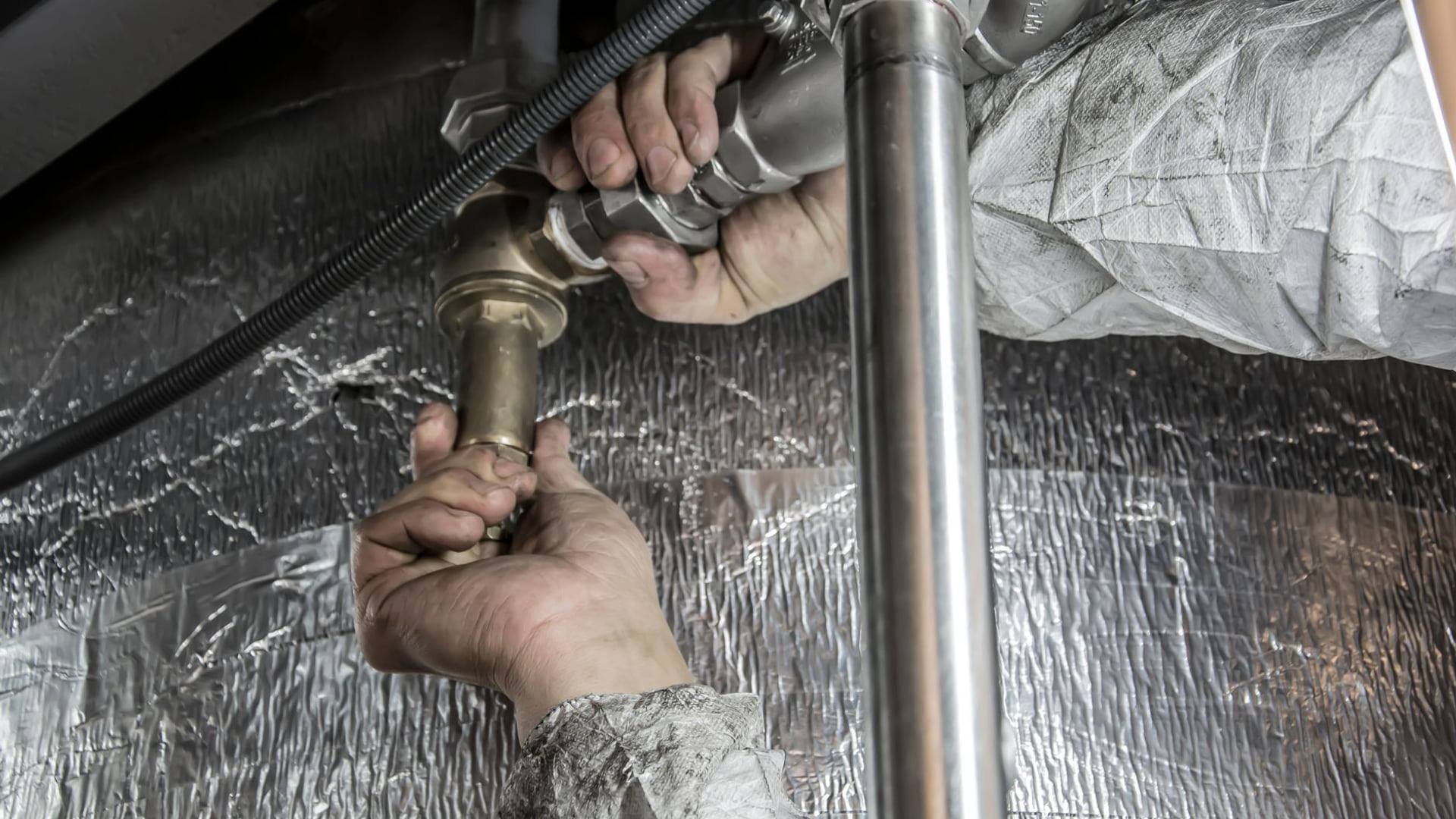 Un technicien inspecte le raccordement d'un système de chauffage moderne à l'intérieur d'un local technique résidentiel.