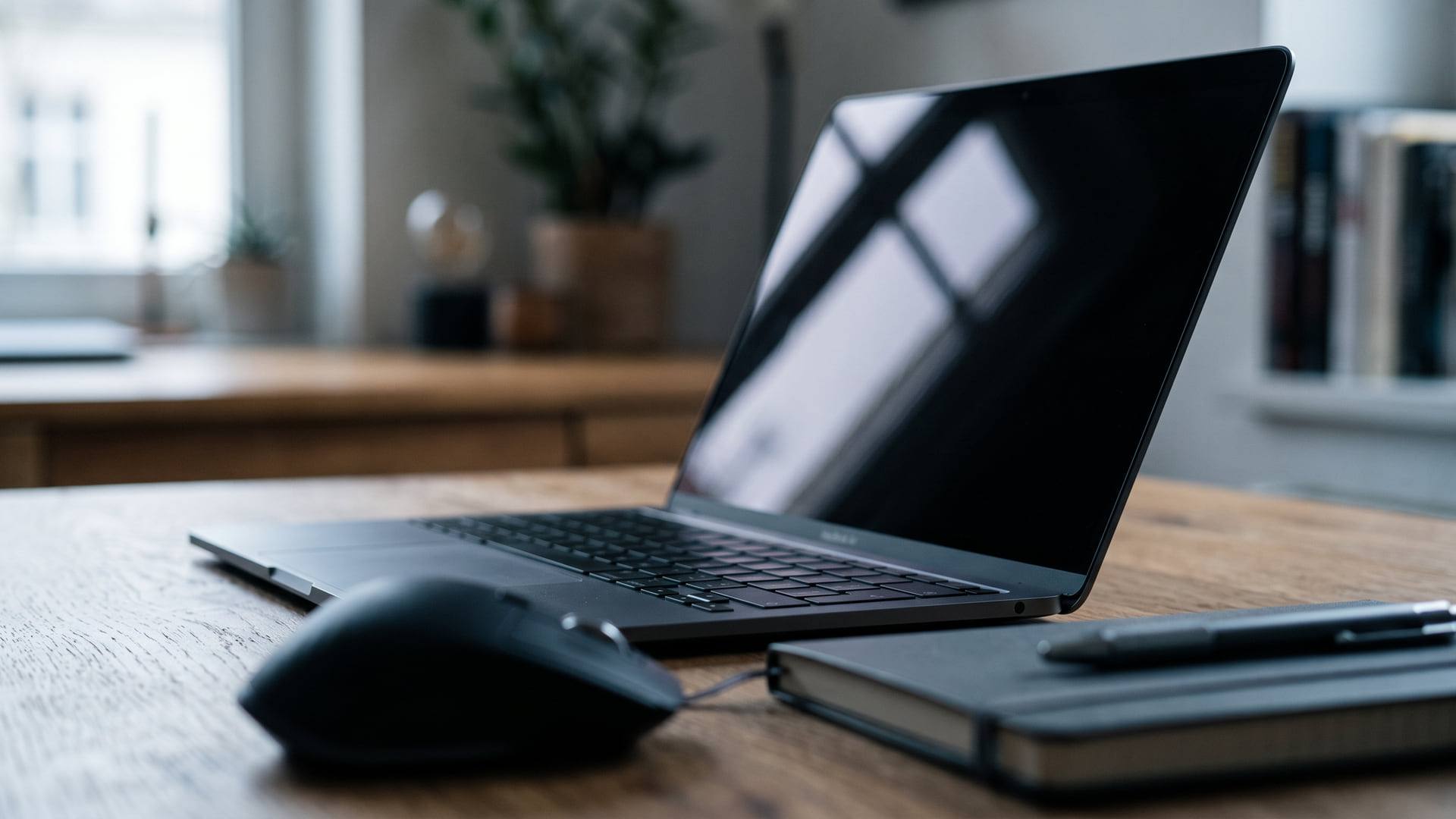 Écran d'ordinateur portable vu de profil, éteint, reflétant la lumière d'une fenêtre