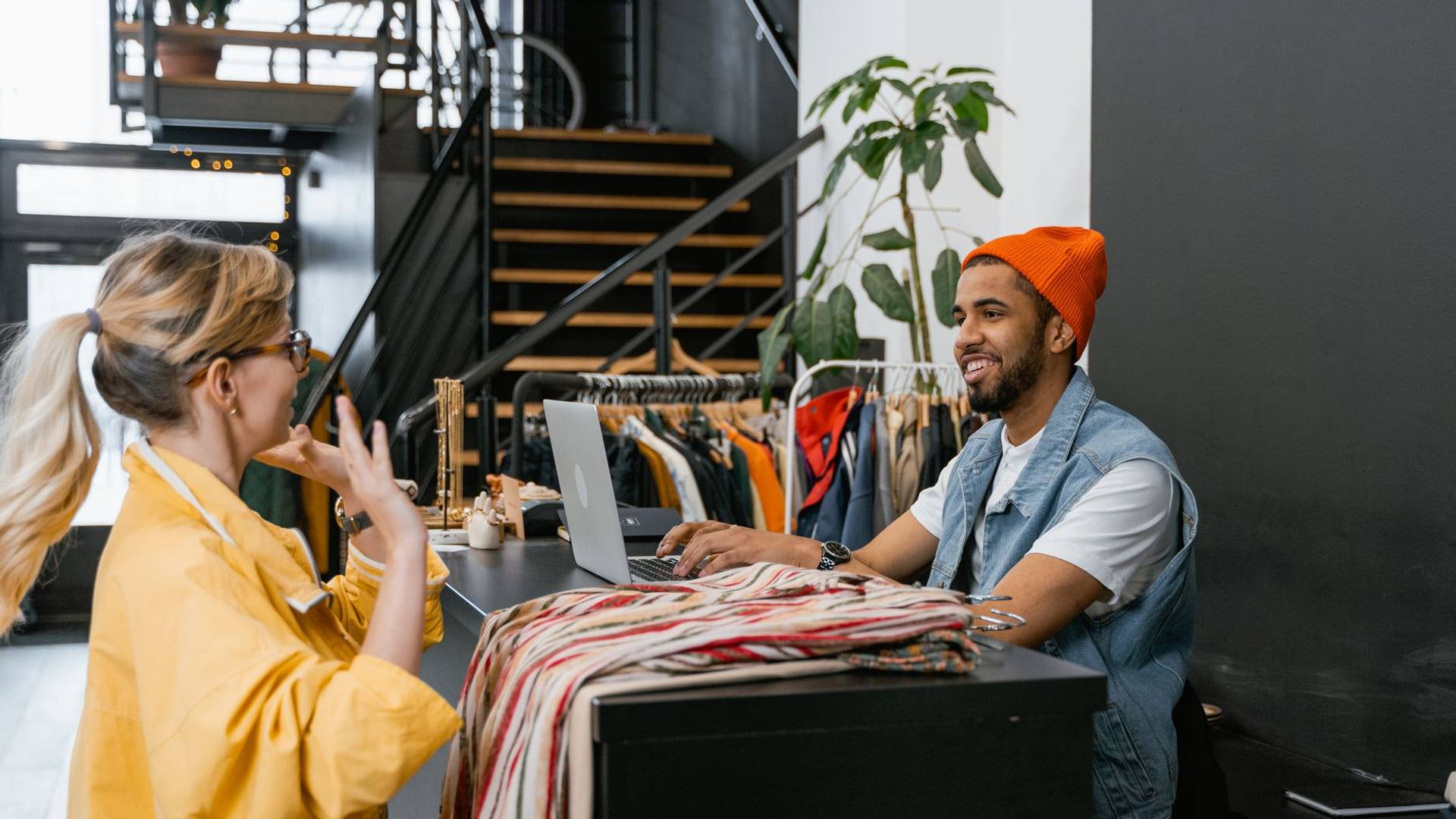 Une cliente au comptoir d'un magasin de vêtements demandant le remboursement d'un article vestimentaire.