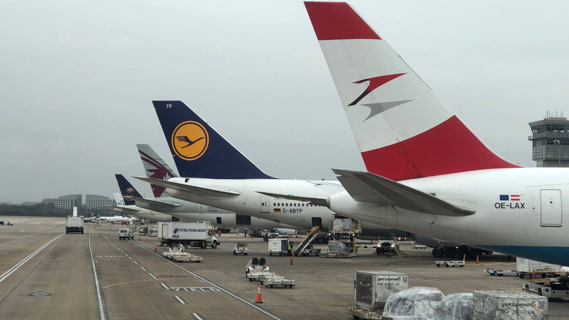Vue sur une tour de contrôle d'aéroport sous un ciel chargé avec des avions stationnés sur le tarmac