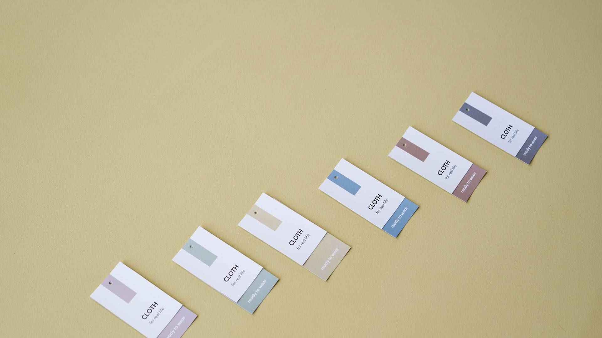 Une personne inspecte les étiquettes de composition et les coutures de plusieurs vêtements disposés sur un portant de seconde main.