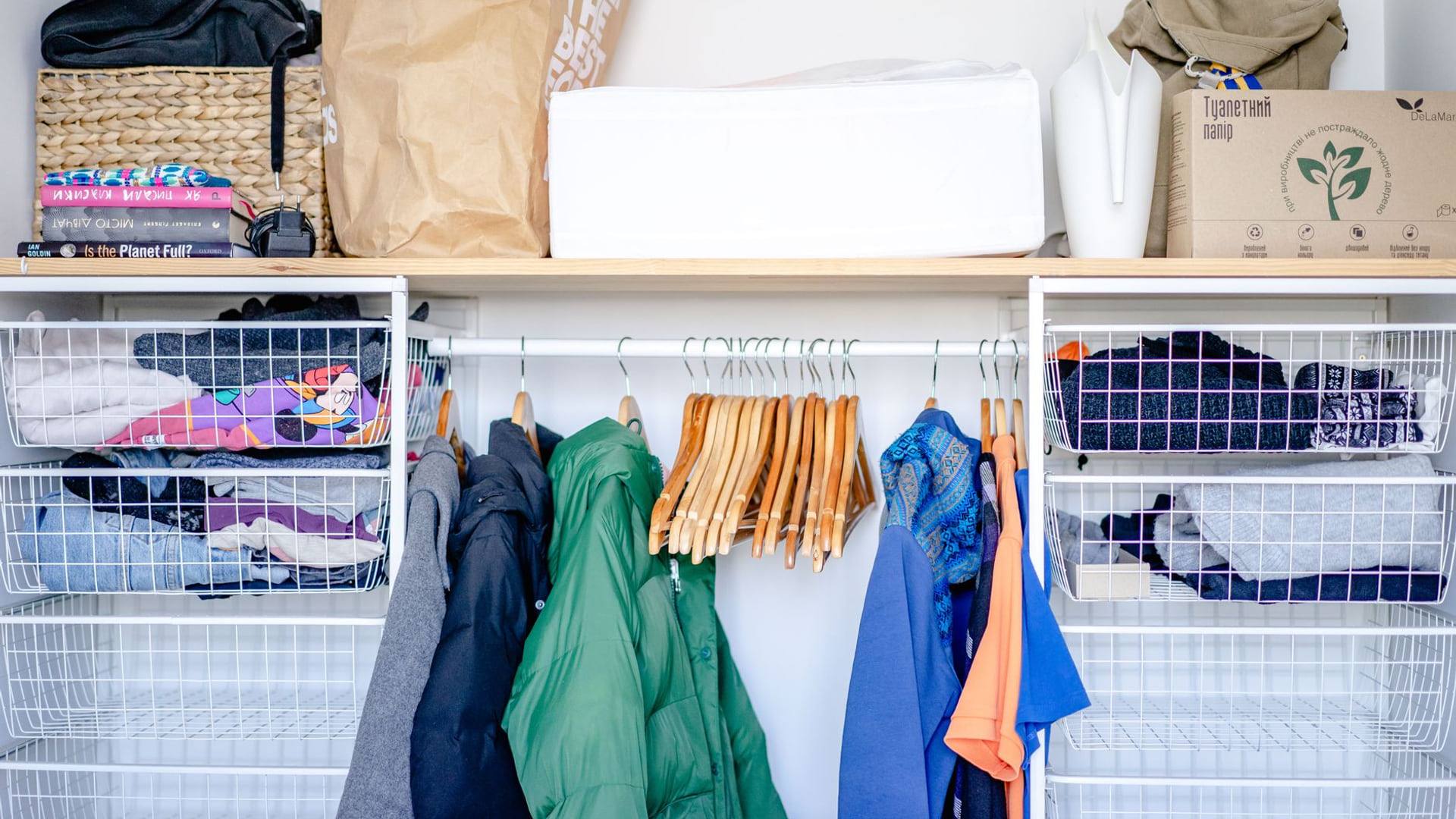Une armoire ouverte contenant une sélection organisée de vêtements suspendus sur des cintres en bois