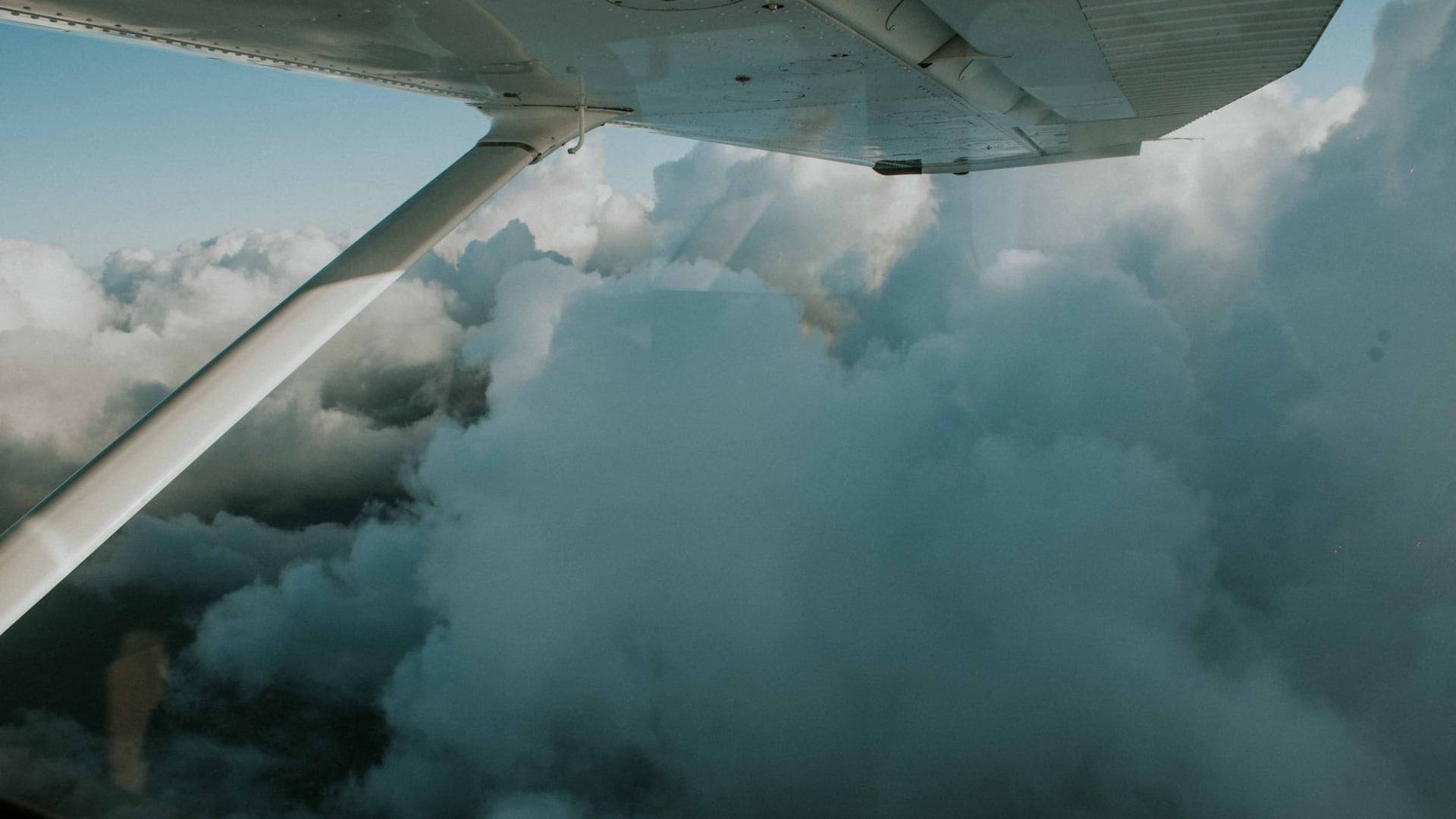 Un hublot d'avion donnant sur des nuages au-dessus d'un paysage forestier