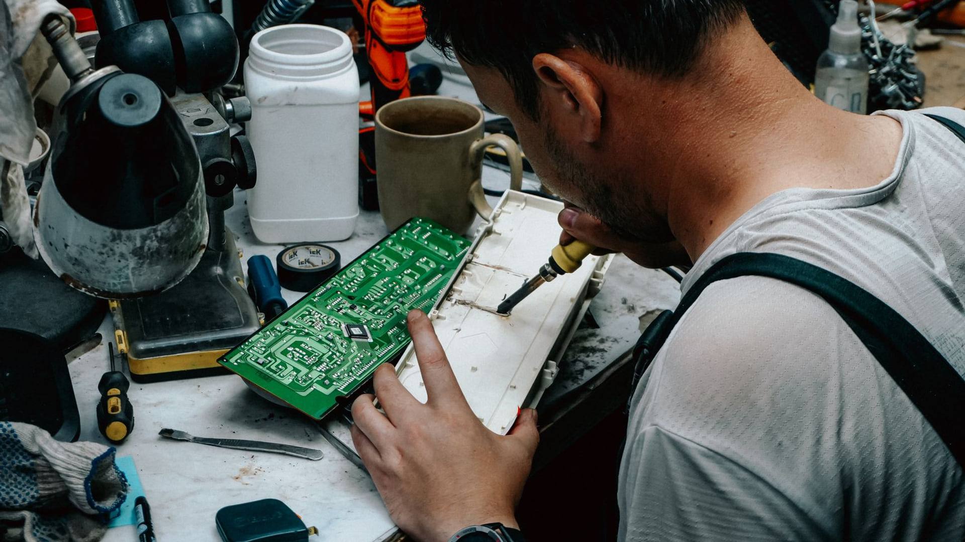 Un établi d'atelier garni d'outils de précision, de composants électroniques et d'un schéma d'appareil ménager