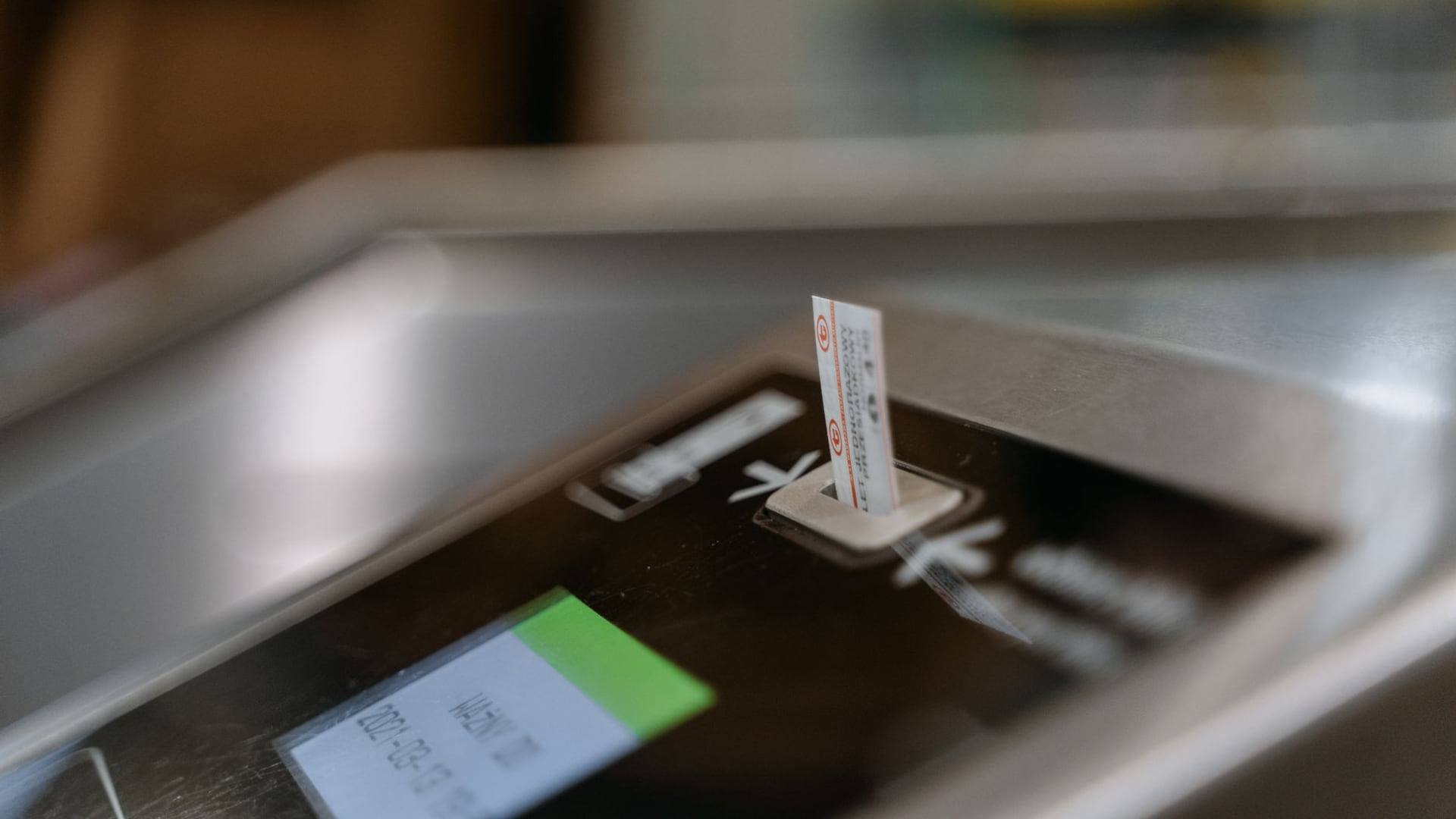 Une personne numérise ses cartes d'embarquement et ses tickets de caisse posés sur une table d'aéroport à côté d'un passeport.