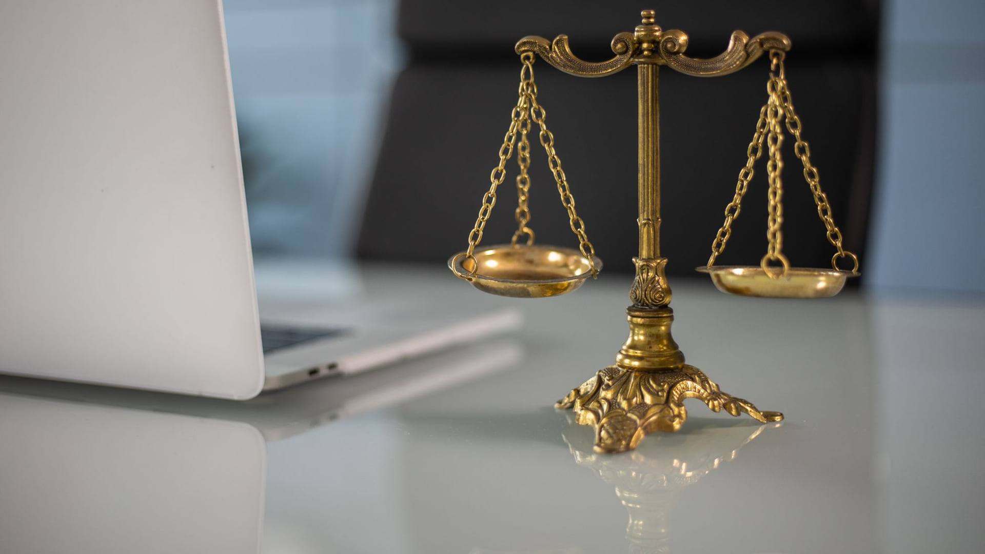 Une balance de la justice posée à côté d'un ordinateur affichant un formulaire d'achat en ligne