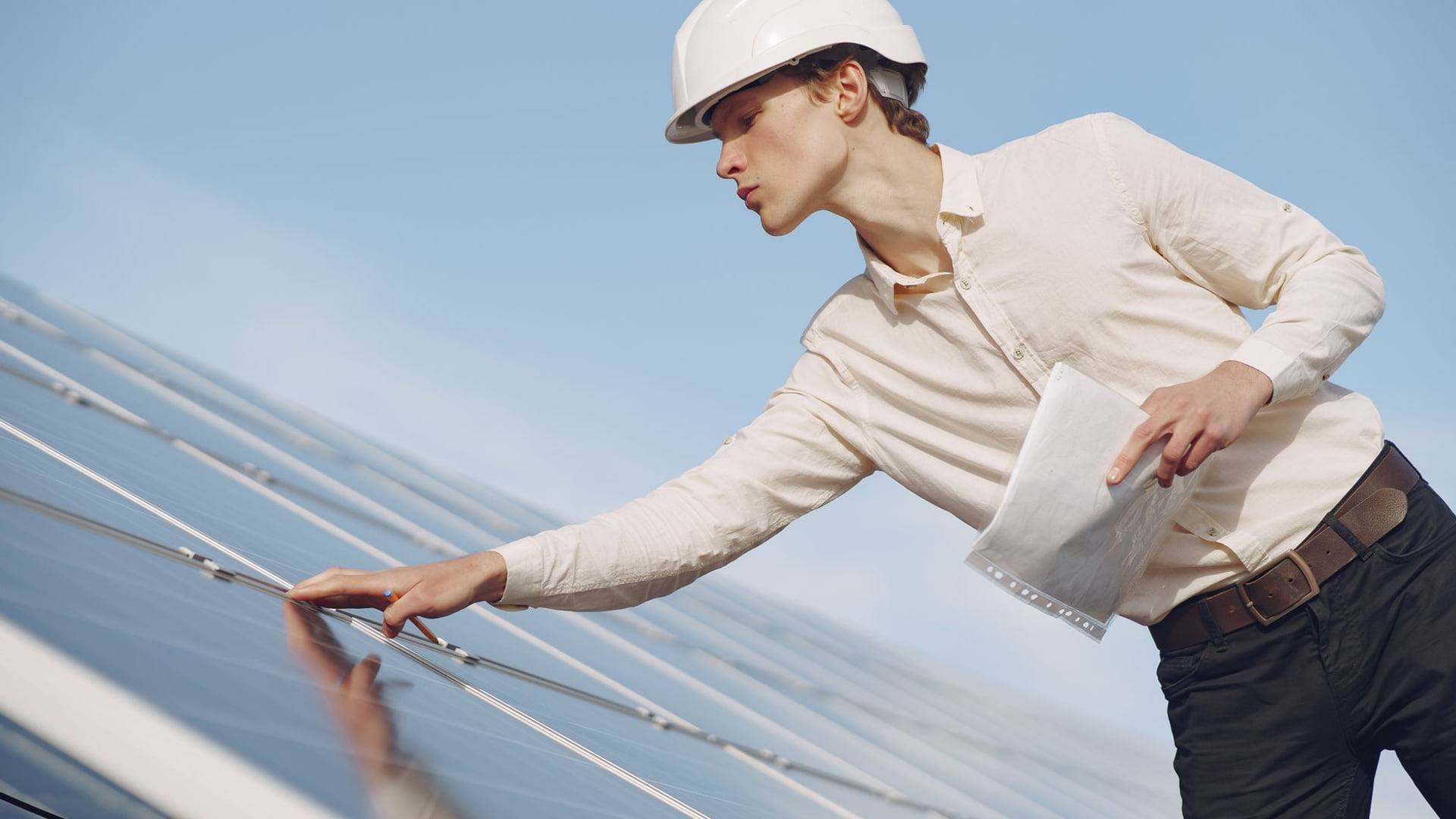 Un artisan vérifiant la pose de panneaux solaires et l'isolation sous les combles d'une maison individuelle.