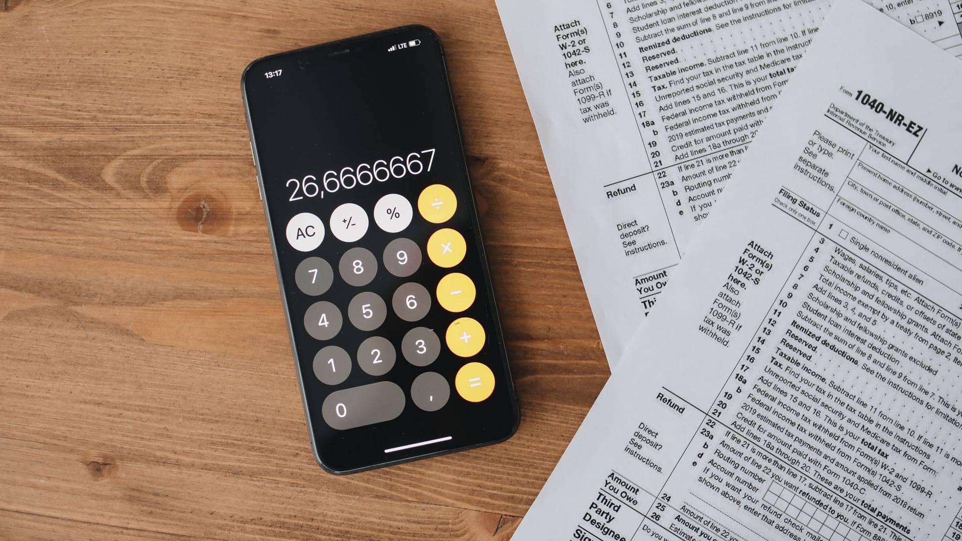 Un smartphone haut de gamme posé sur une table en bois avec une calculatrice et des documents d'analyse de prix