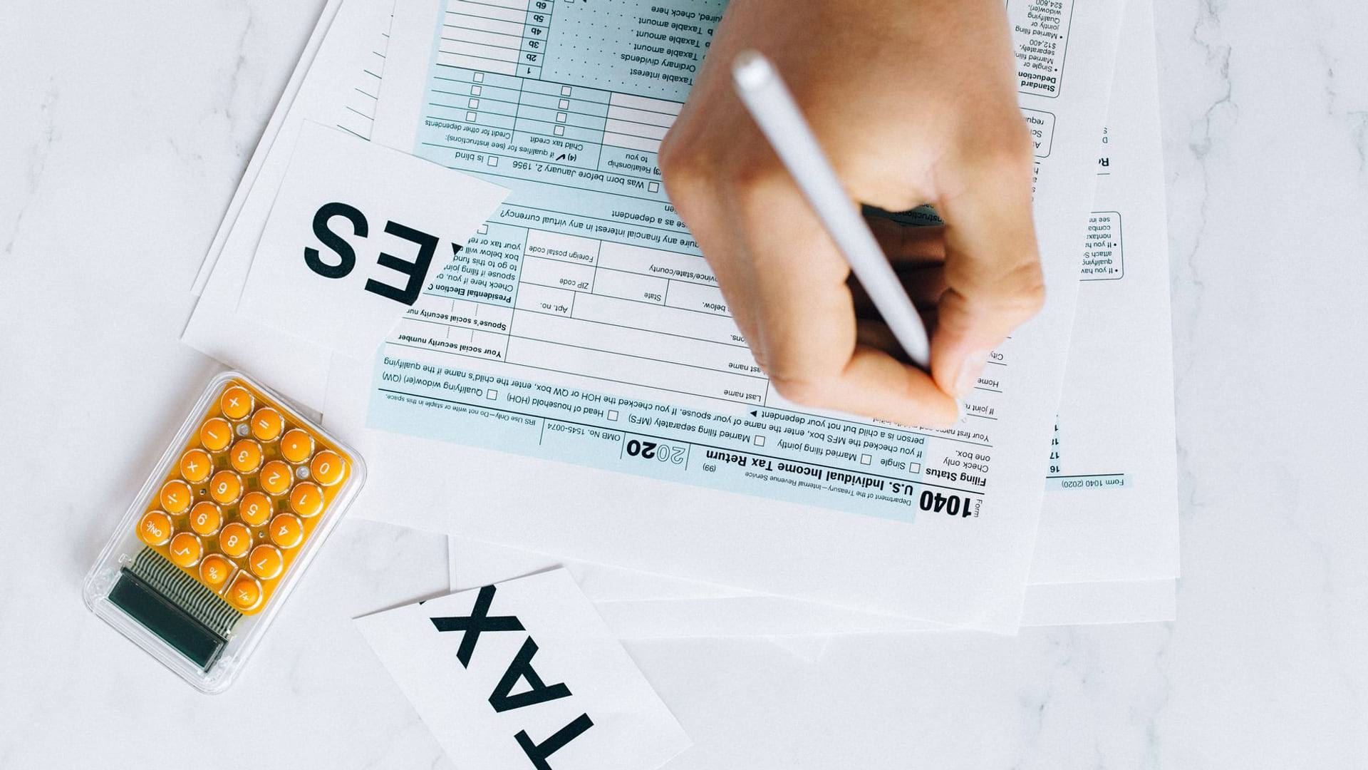 Un propriétaire examinant un avis d'imposition de taxe foncière avec une calculatrice et des documents administratifs posés sur une table en bois.