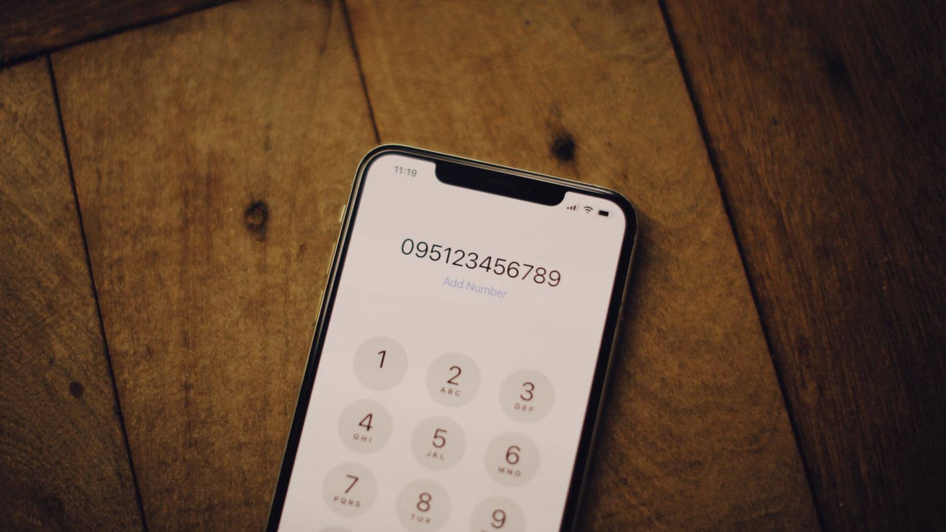 Un écran de smartphone affichant un outil de vérification de numéro de SIRET posé à côté d'un ordinateur portatif.