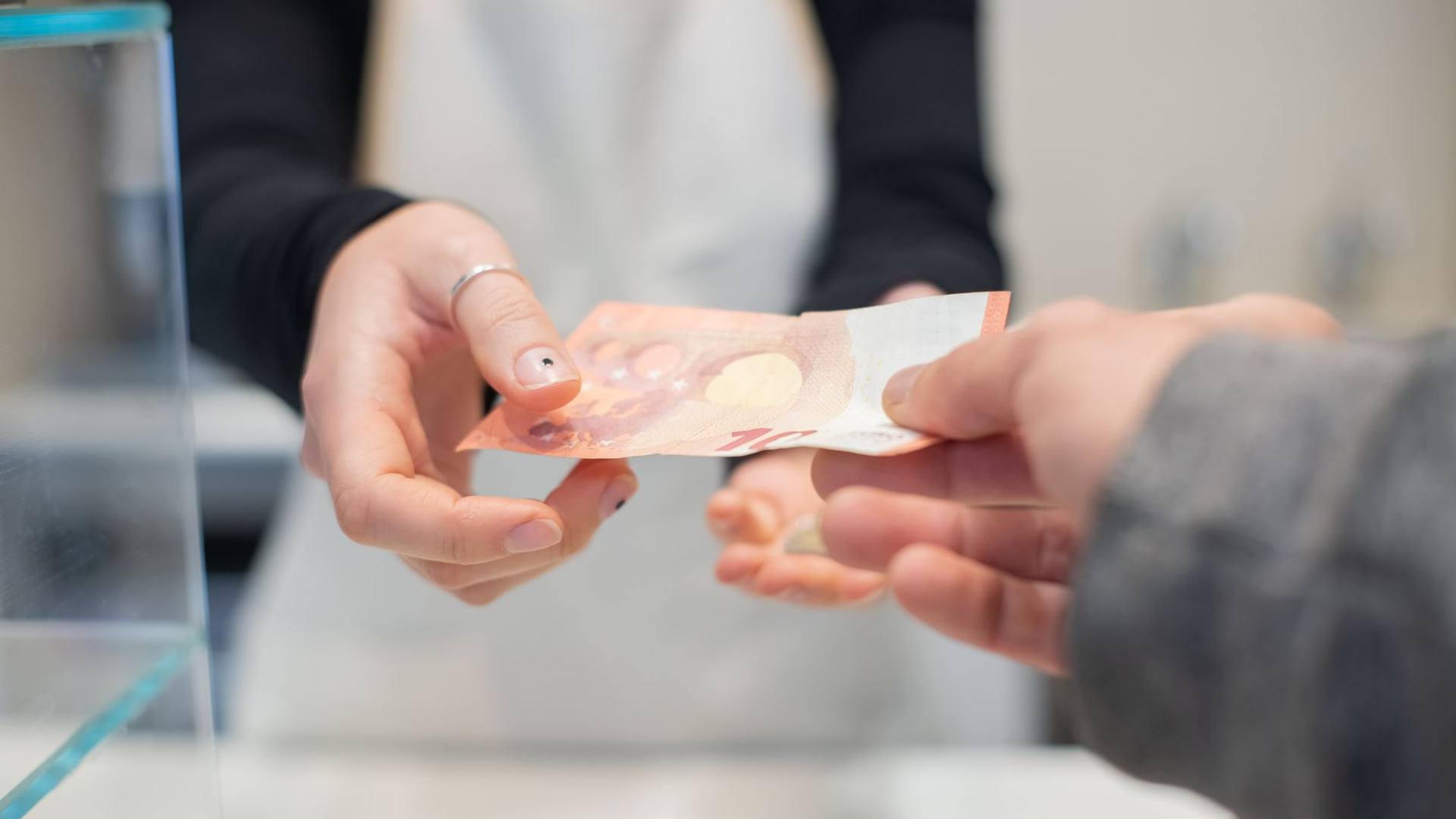 Une personne examinant une facture d'électricité détaillée et un échéancier de paiement posés sur meuble de bureau éclairé.