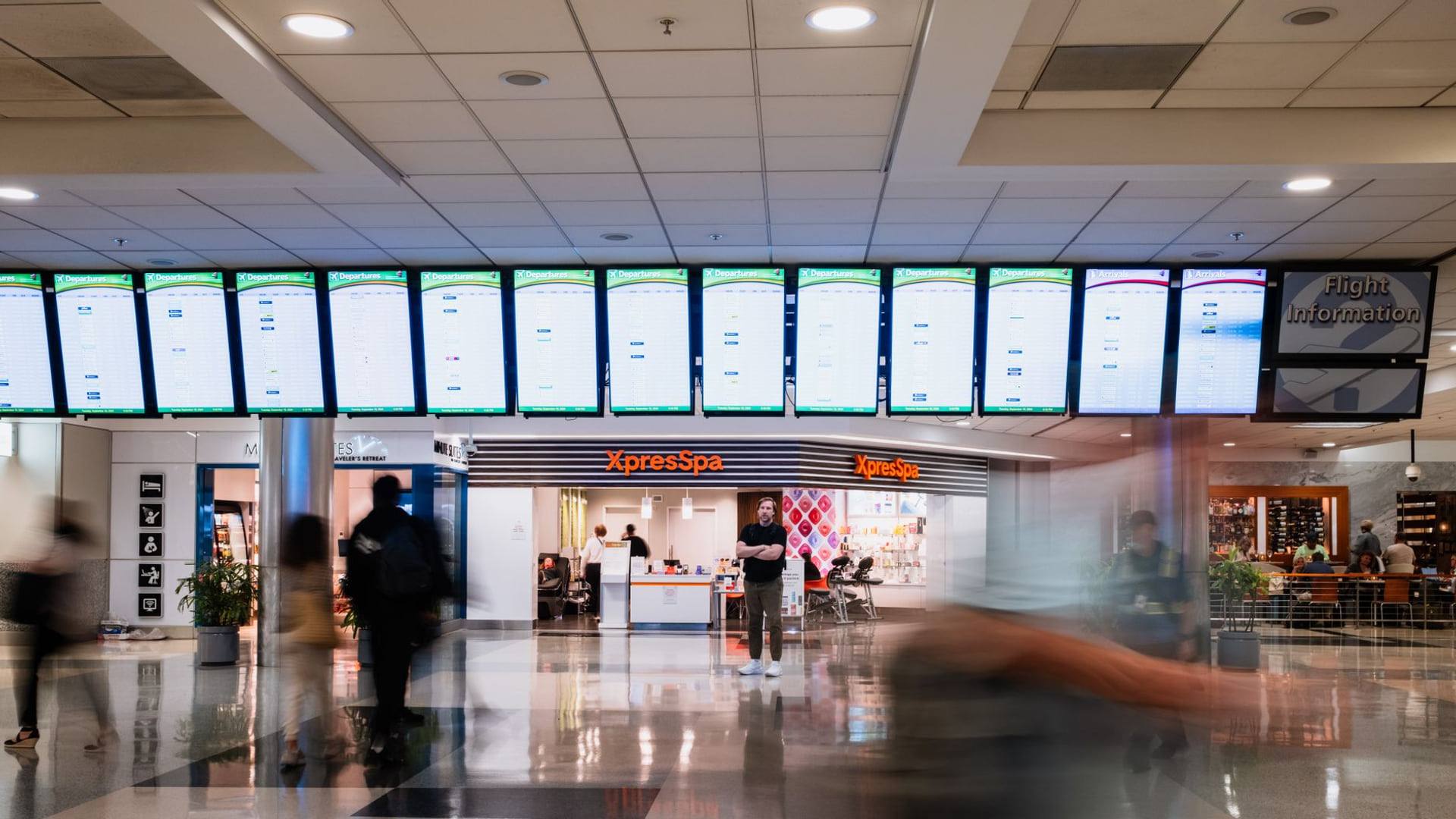 Un écran de départ dans un hall d'aéroport affichant des vols annulés au-dessus de passagers en attente