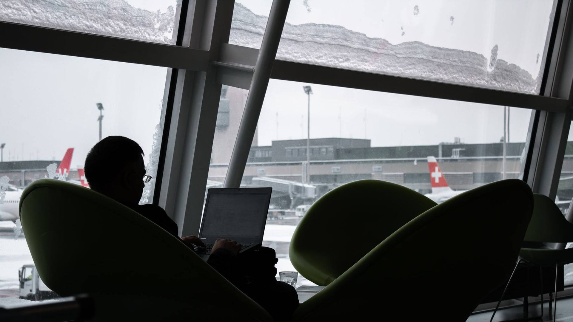 Une voyageuse consulte un dossier juridique sur son ordinateur dans un terminal d'aéroport.